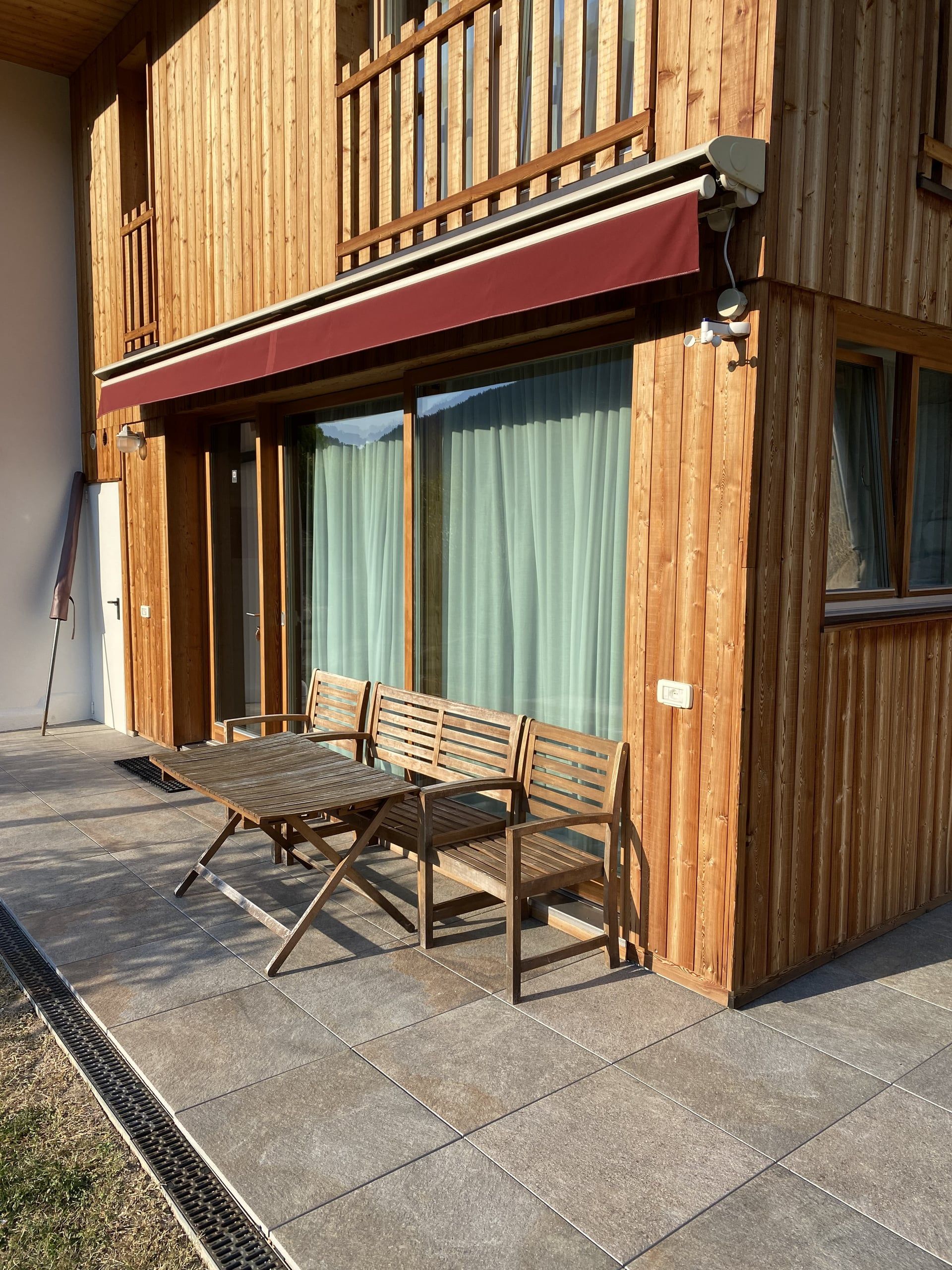 Terrace of the Buche apartment with wooden table and chairs in front of the wooden façade