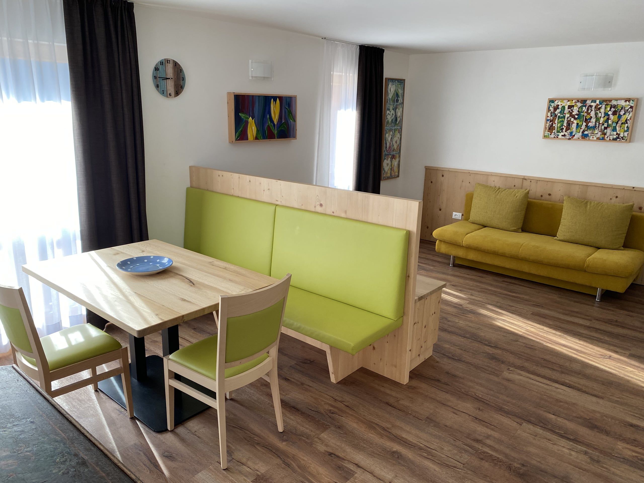 Living room in the Lärche apartment with dining table, green corner bench and yellow sofa
