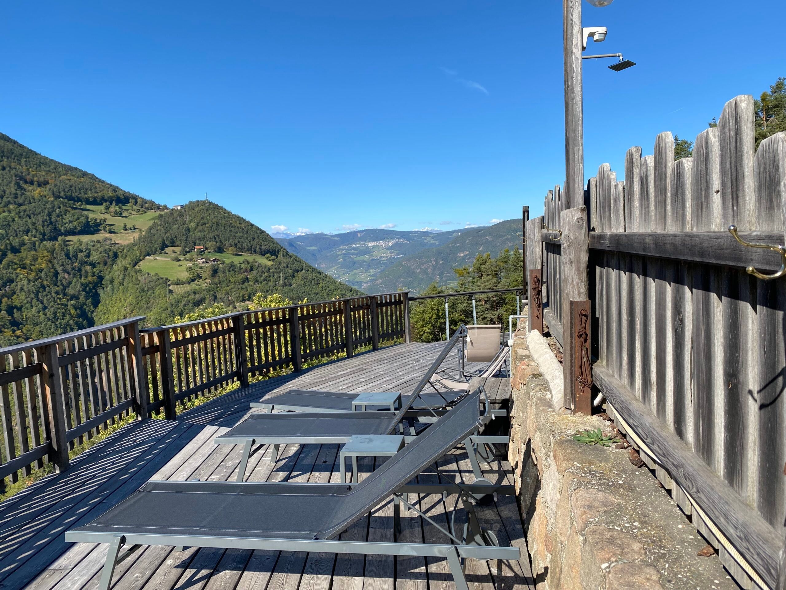 Sonnenliegen auf dem Holzliegesteg mit Blick über das Tal bei blauem Himmel