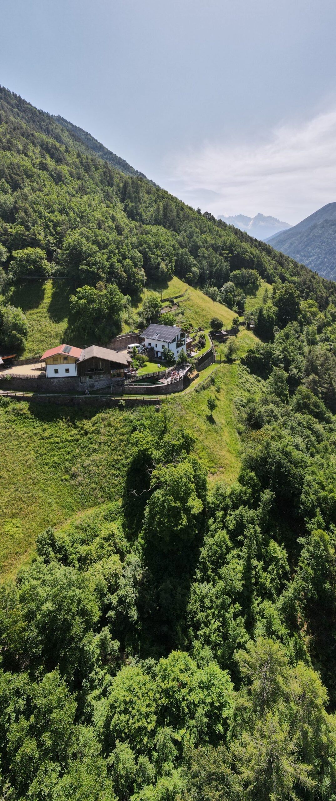 Aerial view of the Brentwaldhof farm buildings on a meadow terrace on a steep slope